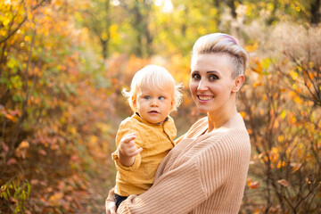 Fototapeta na wymiar mother and son in autumn background with golden trees