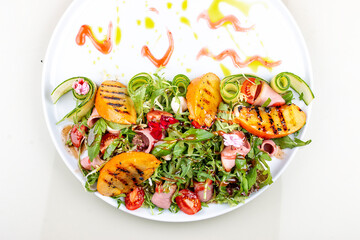 Fresh salad with ham and arugula, with grilled persimmon.