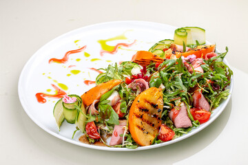 Fresh salad with ham and arugula, with grilled persimmon.