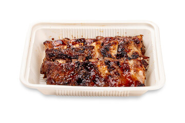 Grilled pork ribs. In a plastic container. Food to go. On a light background.