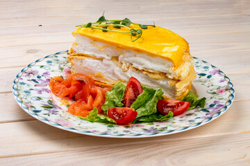 Scrambled eggs layered with salmon and fresh vegetables. Breakfast.
