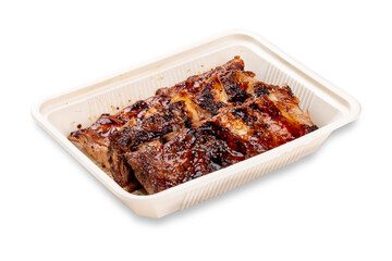 Grilled pork ribs. In a plastic container. Food to go. On a light background.