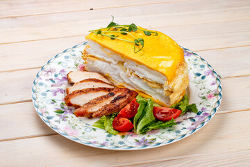 Scrambled eggs layered with fried chicken breast and fresh vegetables. Breakfast.