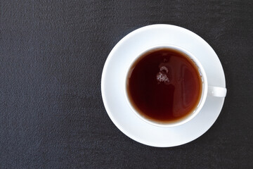 Black tea in a white cup on a dark background