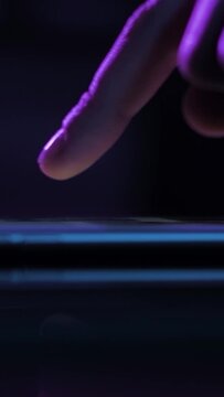 Vertical Video. Young Woman Browsing Internet On Smart Phone At Night; Girls Finger Tapping Keypad, Scrolling Touchscreen Of Mobile Device, Purple Blue Low Light; Extreme Close Up Side View