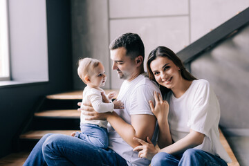 Young happy mother and father with baby daugter playing at home
