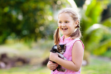 Little girl holding baby cat. Kids and pets