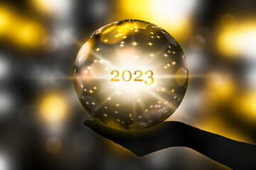 fortunetelling 2023 with a crystal ball in a hand, festive atmosphere for happy new year party or...