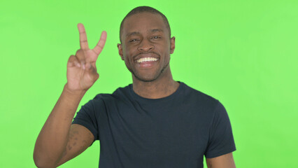 Victory Sign by Young African Man on Green Background
