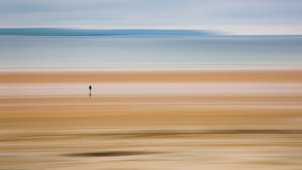Obraz premium lonely, single walker on motion blurred peaceful beach and sea at Dunnet Bay Scotland