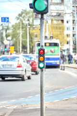 Riga, Latvia - May 13, 2022: Small traffic semaphore with green light against the backdrop of the city traffic.