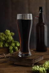 Beer. A tall glass glass of beer, without foam, with hops on an old wooden board. Beer concept. Oktoborfest. Vintage.	