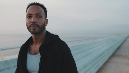 Close up, young bearded male athlete walking along the promenade before training - Powered by Adobe
