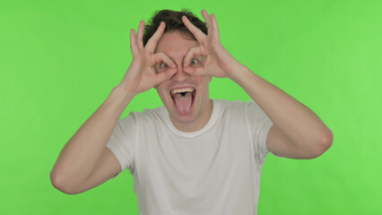 Funny Young Man with Binocular Gesture Searching on Green Background