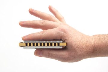 The right hand holds a harmonica on a white background. Classical musical wind instrument.