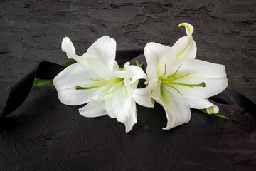 Obraz na płótnie Canvas Flowers heads of white lilies with black ribbon. Mourning or funeral background