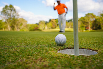 Golfer putting ball on the green golf, lens flare on sun set evening time.