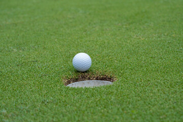 Golf ball on green grass in the evening golf course with sunshine background.
