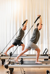 Fototapeta na wymiar Sportsmen exercising on pilates reformer beds