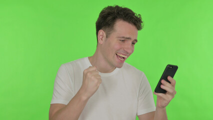 Young Man Celebrating on Smartphone on Green Background