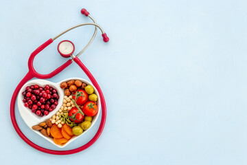 Cholesterol diet concept. Healthy food in heart shaped dish with stethoscope