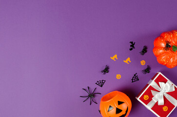 Red gift box and traditional halloween decorations on purple background,copy space. Halloween Gifts and Sale