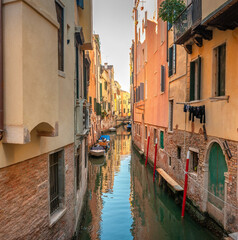 Fototapeta na wymiar View on the narrow cozy streets of the canals with parked boats in Venice, Italy. Architecture and landmark of Venice.