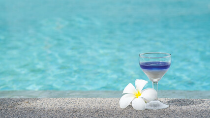 Glass of welcome drink at infinity swimming pool with ocean background. cocktail with alcohol and without alcohol by the pool.