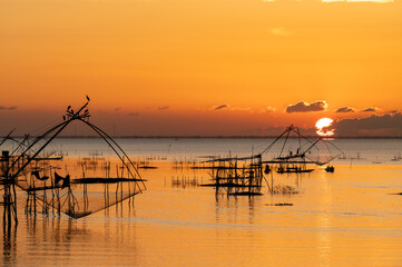 Fototapeta na wymiar Square dip net in lake with sunrise at Pak pra village, Phatthalung, Thailand