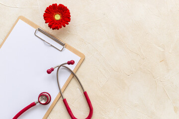 White blank of doctor gynecologist clipboard with red flower and stethoscope