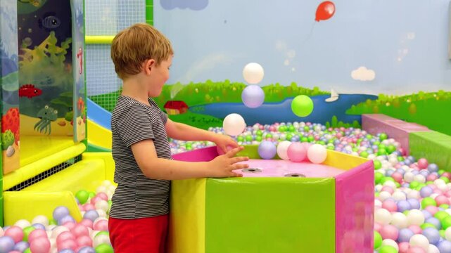 European blond hair 4-6 years old boy in entertaimen room playing with flying balls toys.Smiling toddler in playing centre.Cute childrenin dry pool.Development and construction concept. . High quality