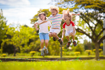 Happy kids play outdoor. Children skipping rope. - obrazy, fototapety, plakaty