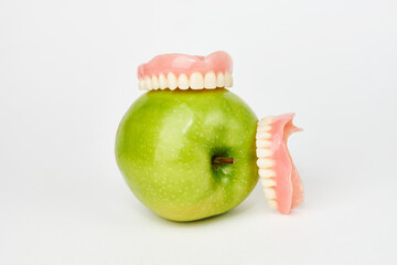 Green apple and dentures on white background