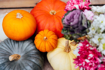 Top view various pumpkins and flowers in the wicker basket. Harvest in autumn season. Fall, thanksgiving or Halloween background. Selective focus