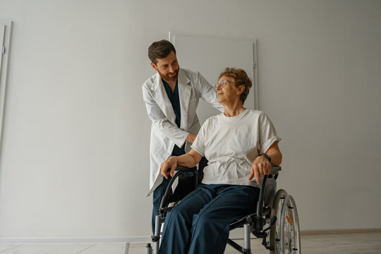 Professional male doctor carrying patient on wheelchair in medicine clinic hall. High quality photo - Powered by Adobe