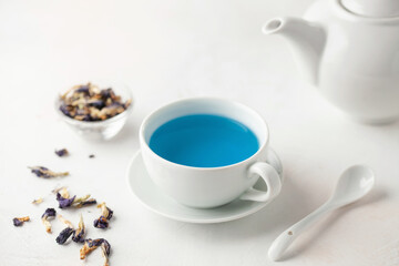 Obraz na płótnie Canvas Thai blue Anchan tea in a white cup and teapot on a wooden background.
