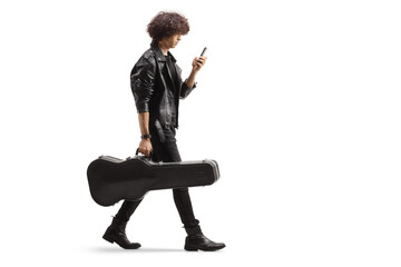 Full length profile shot of a young musician carrying a guitar case and using a smartphone