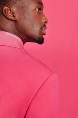 Fashion profile portrait of stylish african man with fashionable pink jacket on pink background.