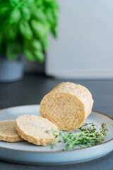 Raw Tempeh or Tempe, made of fermented soybean seeds on kitchen table. Tempeh Slices on the plate. Soya protein. Plant based meat. Healthy eating. Go vegan. Vertical card. Selective focus, copy space