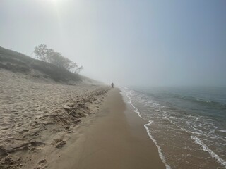 Para ludzi na pustej plaży o poranku podczas mgły.