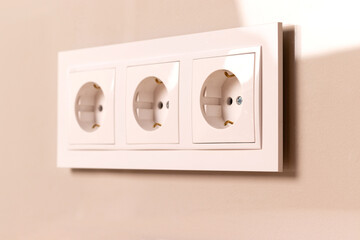 Group of white european electrical outlets on modern beige wall. Selective focus