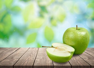 Fresh tasty ripe apples on a wooden table in a garden