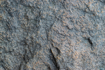 Raw gray granite rock texture background. Fragment of natural stone wall