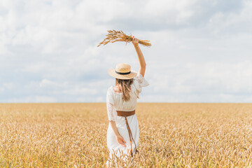 Fototapeta na wymiar girl in a white dress in a field of ripe wheat