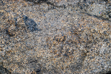 Raw gray granite rock texture background. Fragment of natural stone wall