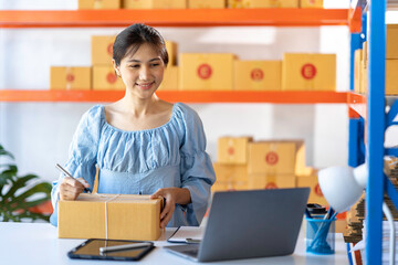 SME entrepreneur Small business entrepreneurs Online selling ideas,Happy Young Asian business owner work on computer and a boxs at home,delivery SME procurement package box deliver to customers