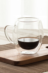 Bubble glass  cup of coffe backlighted on a wooden board on a tablecloth. Warm colors.