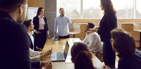 Business team during morning briefing in office discussing ideas and exchanging interesting ideas. Cheerful multiracial colleagues are brainstorming and sharing opinions at big table. Web banner.