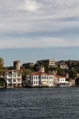 Obraz premium View of historical, traditional mansions and old Anatolian fortress by Bosphorus in Anadolu Hisari area of Asian side of Istanbul. It is a sunny summer day. Beautiful travel scene.