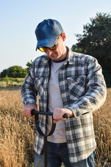 Male agronomist taking sample with soil probe sampler at agricultural field at sunrise. Farmer using drilling tool for soil sampling at morning outdoors. Environment research, soil certification